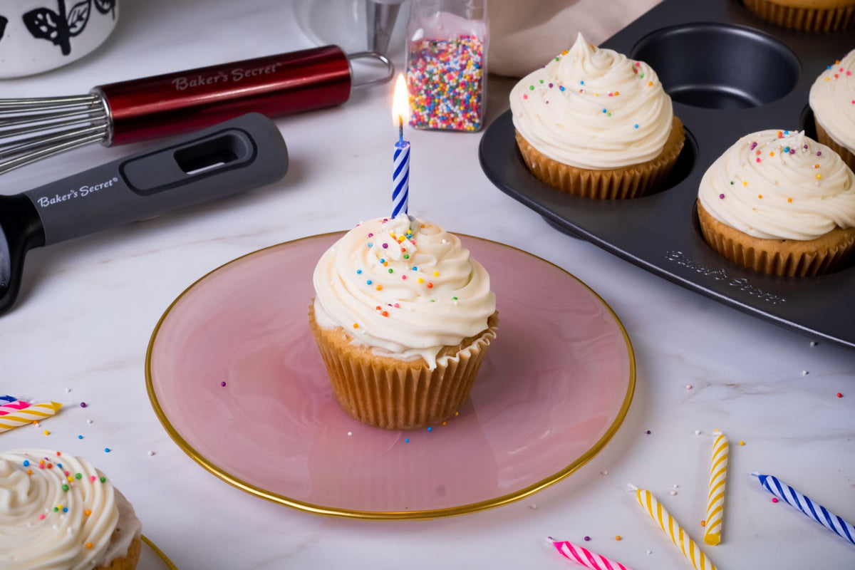 Birthday cupcake with a lit candle on a pink plate