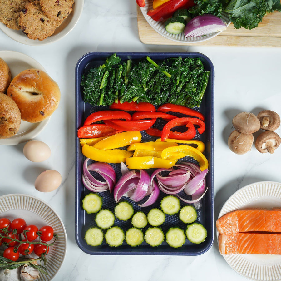 Bell peppers, zucchini, broccoli and onion arranged on a sheet pan for roasting