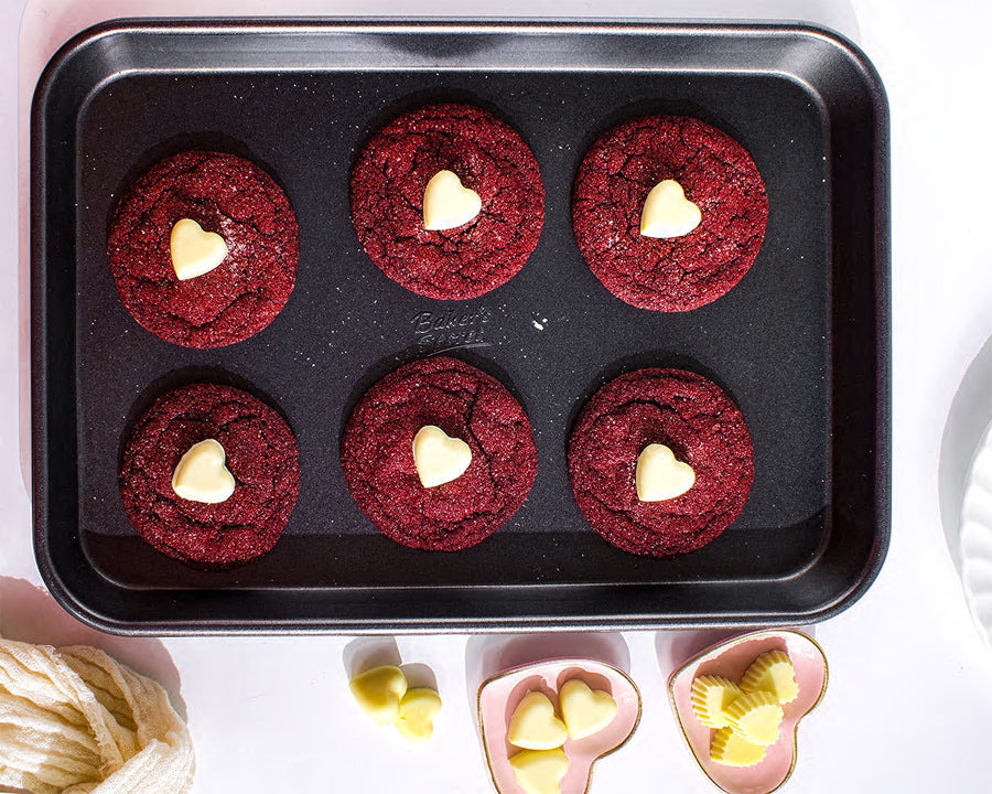 Red velvet sugar cookies with white heart centers in a baking pan