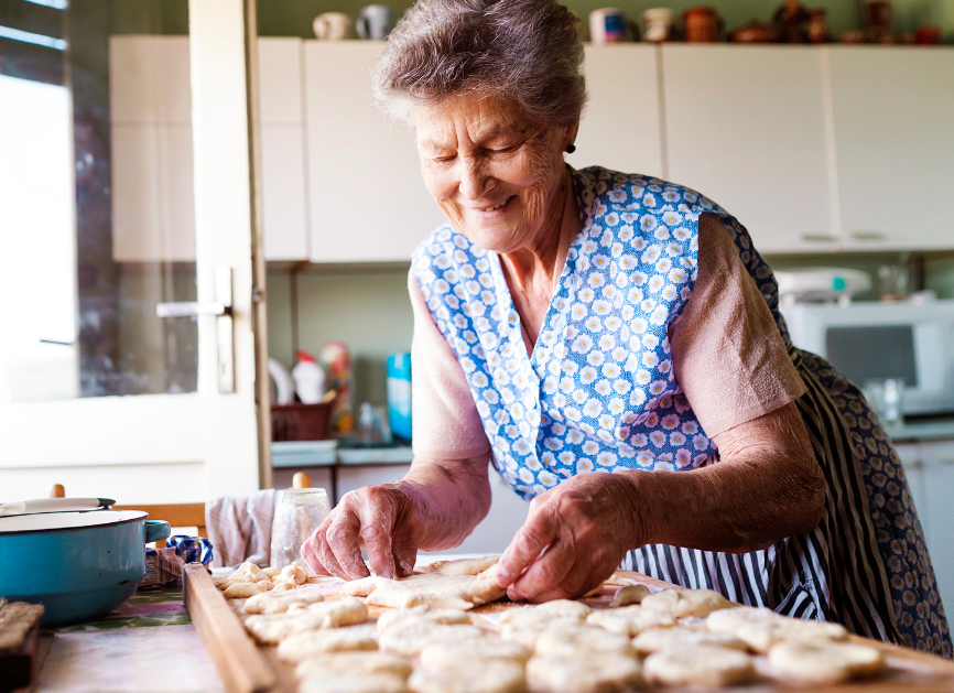 Grandmother cutting out cookies in a sunny kitchen