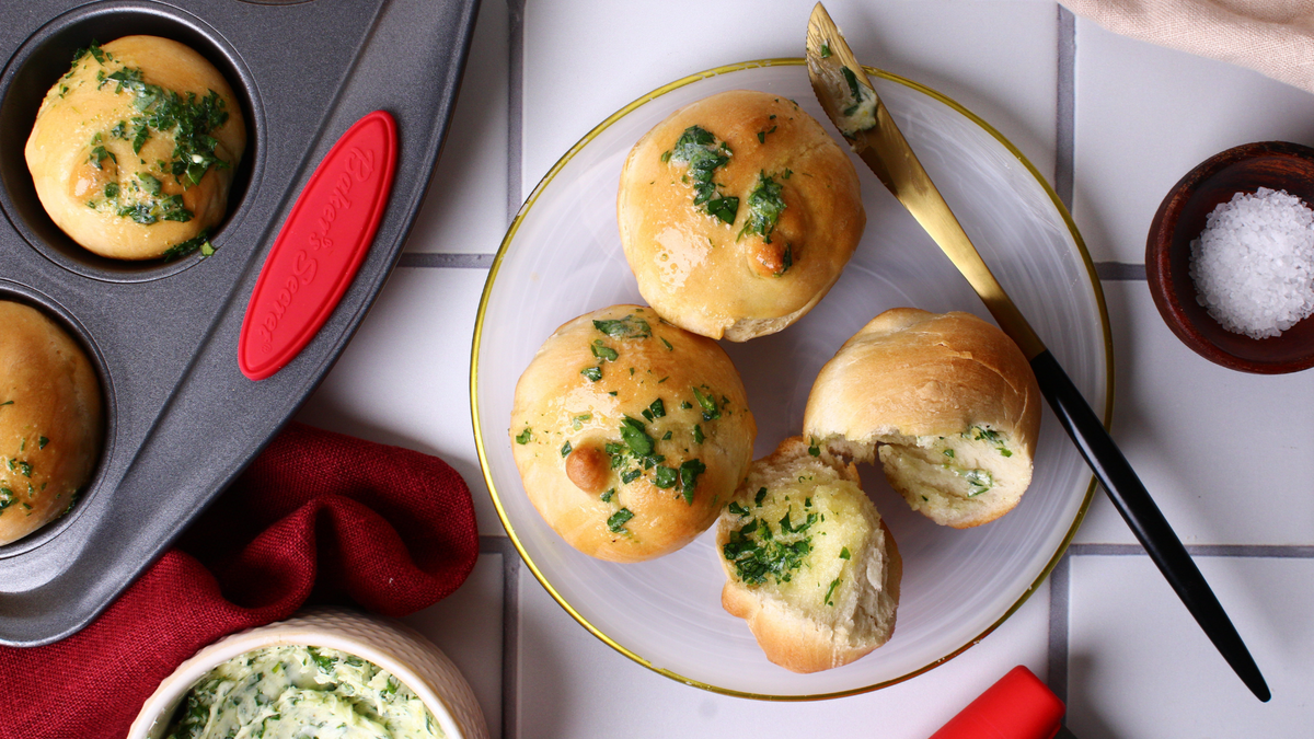 Golden garlic knots brushed with herb butter on a plate