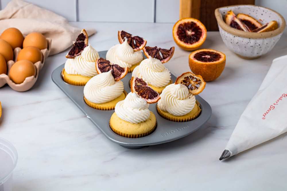 Blood orange cupcakes topped with cream and blood orange slices