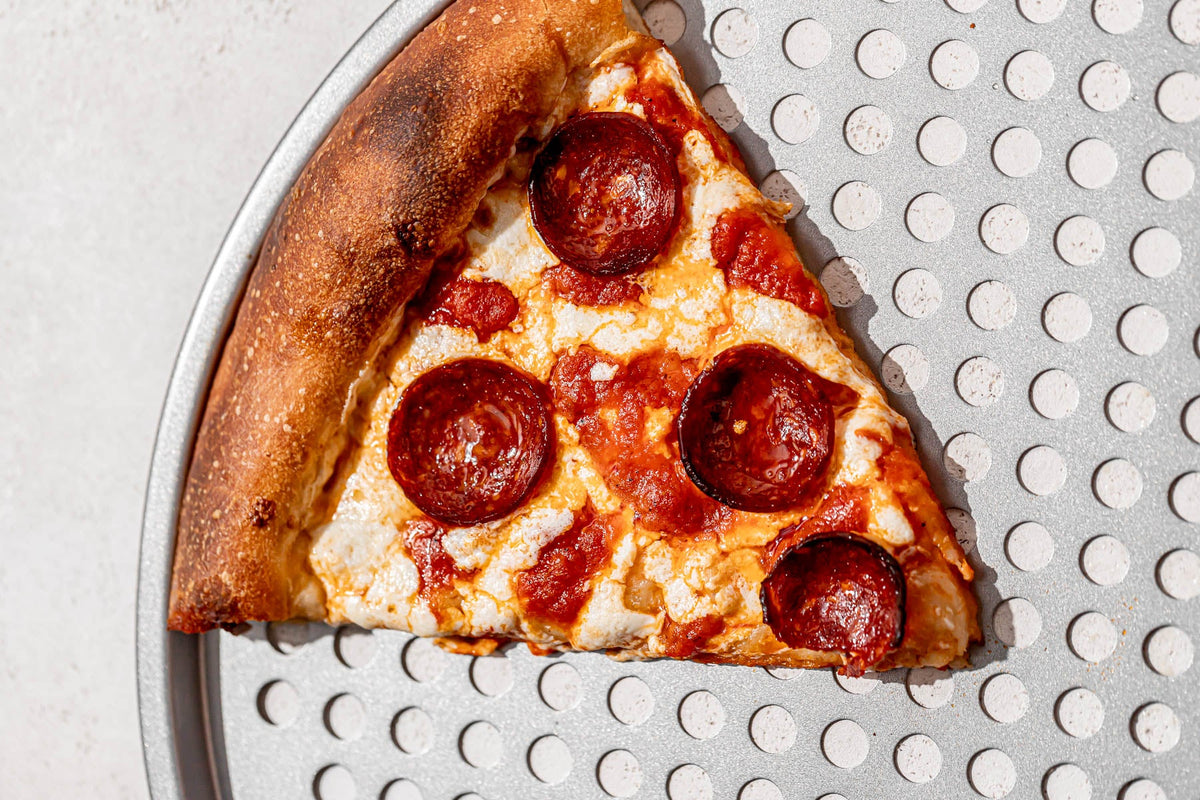 Slice of New York-style pepperoni pizza on a pizza crisper