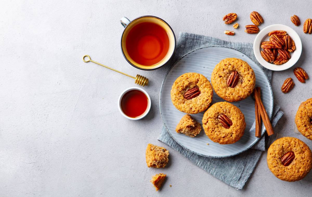 Pecan shortbread cookies on a plate next to a cup of tea