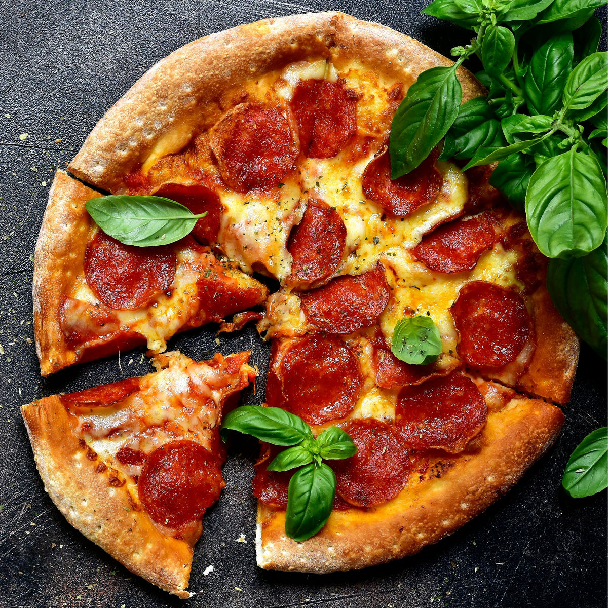Pepperoni pizza with fresh basil on a pizza pan