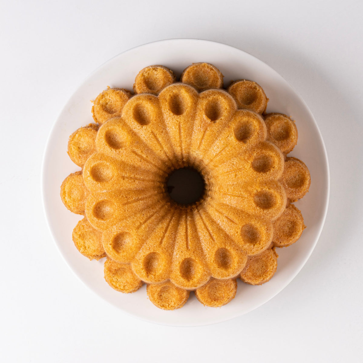 Golden Marquise fluted cake on a white plate, top view