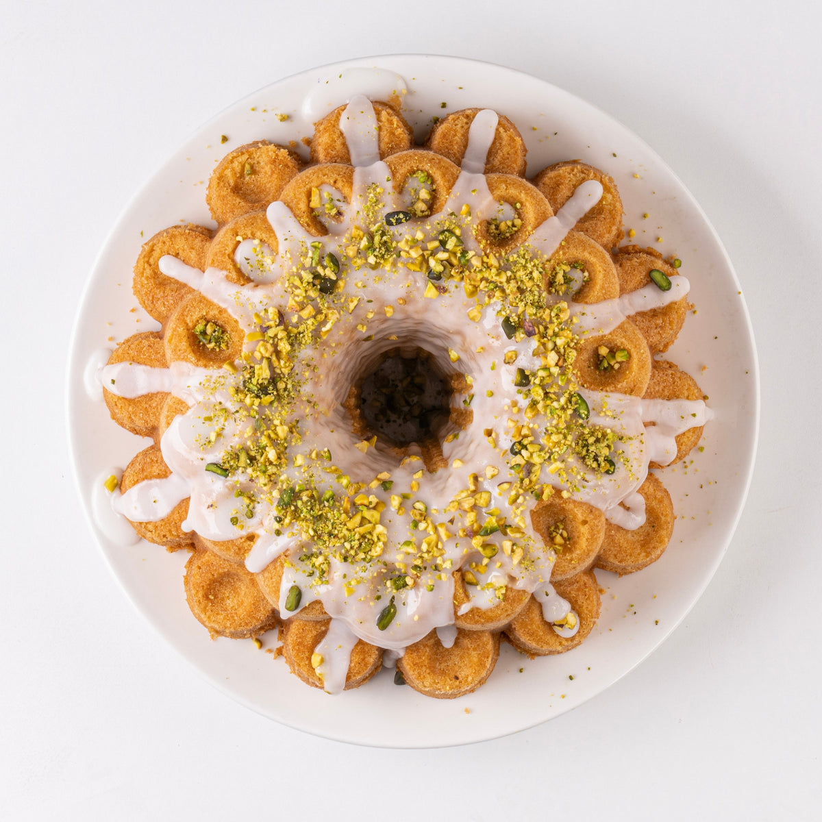 Fluted cake with white glaze and chopped pistachios, top view