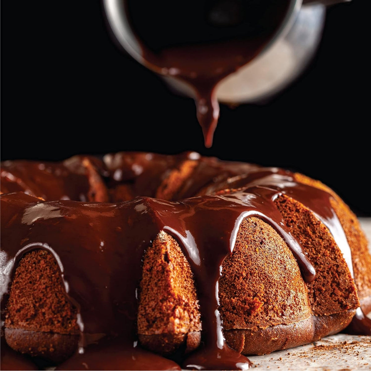 Chocolate glaze being poured over a fluted cake