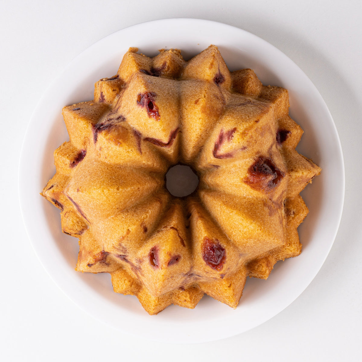 Golden Cascade fluted cake with cranberries on a white plate