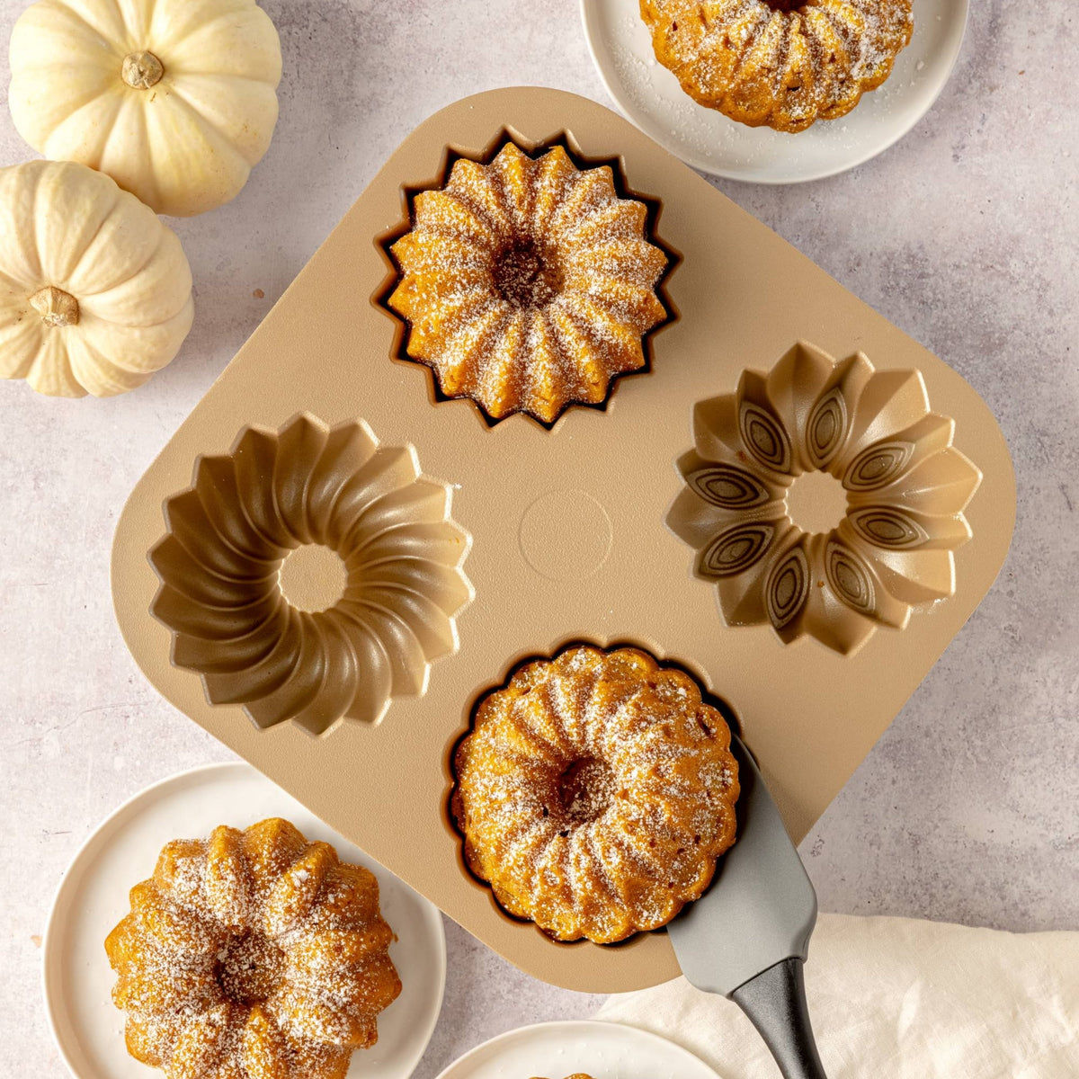 Mini Joys pan with four golden mini fluted cakes and small pumpkins, top view