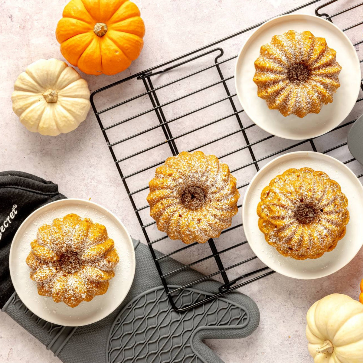 Mini fluted cakes cooling on a wire rack with small pumpkins